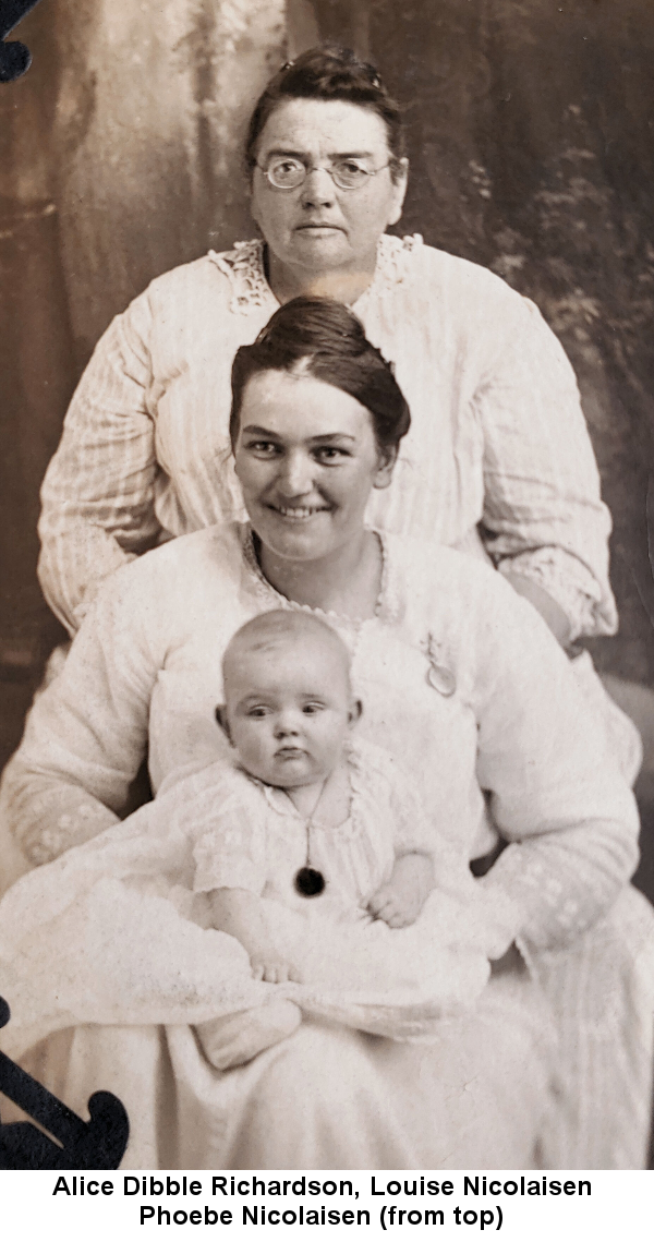 Sepia-tone photo of serious-faced Alice Dibble Richardson, wearing round wire-frame glasses, her hair in a tight bun, standing, with her daughter Louise Nicolaisen, smiling, her hair piled on top of her head,seated in front of her with a blond baby, Phoebe Nicolaisen, on her lap; all are wearing white dresses.
